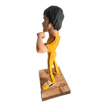 Limitierte Resin-Figur in dynamischer Pose, Seitenansicht, mit ikonischem gelben Trainingsanzug und Sockel in Holzoptik